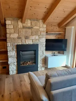 a living room with a couch and a fireplace at Casa Zena in Tesero