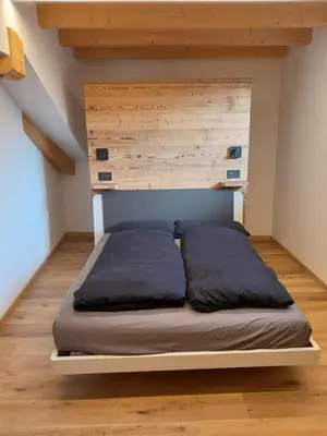 a bed in a room with a wooden wall at Casa Zena in Tesero