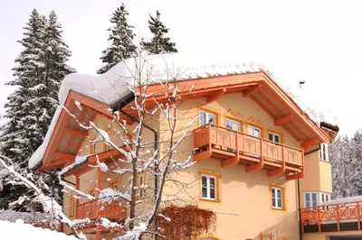 a house with a balcony in the snow at Ferienwohnung BERGKLANG in Nova Ponente