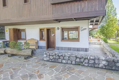 a home with a stone patio and a building at Ca Tambres dimora nelle Dolomiti in San Vito di Cadore