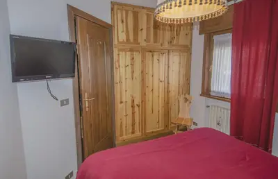 a bedroom with a bed and a flat screen tv at Ca Tambres dimora nelle Dolomiti in San Vito di Cadore