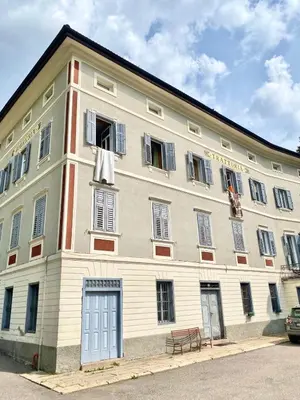 a large white building with a blue door and windows at All'antica Birreria in Predazzo