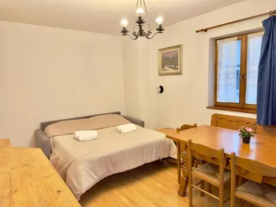 a bedroom with a bed and a wooden table at Casa Cortina 3 camere da letto e parcheggio in Cortina dʼAmpezzo