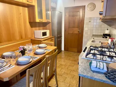 a kitchen with a table with chairs and a stove at Casa Cortina 3 camere da letto e parcheggio in Cortina dʼAmpezzo