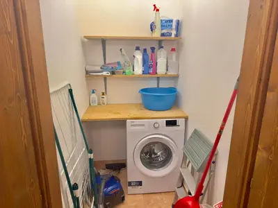 a laundry room with a washing machine and shelves at Casa Cortina 3 camere da letto e parcheggio in Cortina dʼAmpezzo