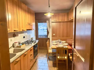 a kitchen with wooden cabinets and a small table with chairs at Casa Cortina 3 camere da letto e parcheggio in Cortina dʼAmpezzo