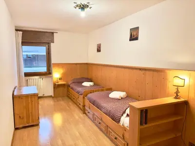 a bedroom with two beds and a window at Casa Cortina 3 camere da letto e parcheggio in Cortina dʼAmpezzo