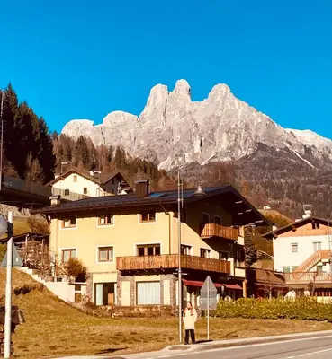 a person standing in front of a building with a mountain at primiero-suite 45mq in Transacqua