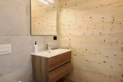 a bathroom with a sink and a wooden wall at Ciesa Le Crepedele - Miniappartamento Zirum in Sottoguda
