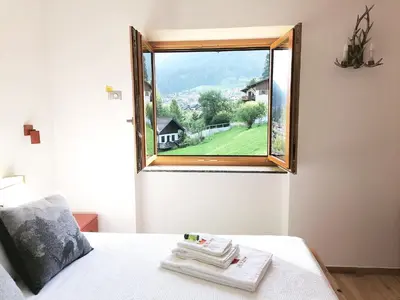 a bedroom with a window with towels on a bed at Villa Re Laurino Suite Respiro del bosco in Moena