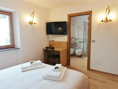a bedroom with a bed with two towels on it at Villa Re Laurino Suite Respiro del bosco in Moena
