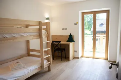 a room with bunk beds and a desk with a window at Villa Re Laurino Suite Respiro del bosco in Moena