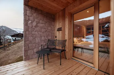 a room with a chair on a wooden deck at Resciesa Hof in Ortisei