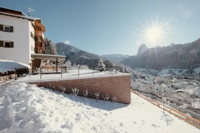 a snow covered building with the sun in the background at Resciesa Hof in Ortisei