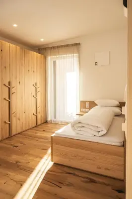 a bedroom with a bed with wooden cabinets and a window at Residence Louise in Vipiteno