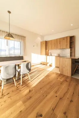 a kitchen with wooden floors and a table and chairs at Residence Louise in Vipiteno