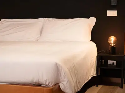 a bed with white sheets and a light on a table at Grifone Dolomiti Residences in Arabba