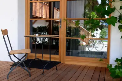 a chair and a table on a porch next to a window at Apartments Mitterhof 1544 in Brunico