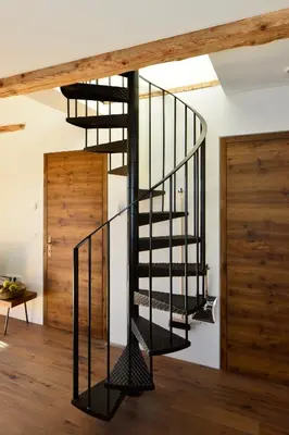 a spiral staircase in a room with wooden floors at Apartments Mitterhof 1544 in Brunico