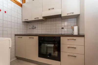 a kitchen with white cabinets and a black oven at Appartamento Cordevole PT in Caprile