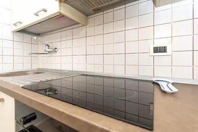 a kitchen with a sink in a white tiled wall at Appartamento Cordevole PT in Caprile
