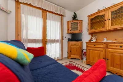 a living room with a blue couch and a window at Appartamento Cordevole PT in Caprile