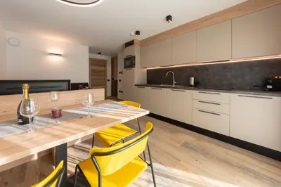 a kitchen with a wooden table and yellow chairs at Vacanze la Malga in Predazzo