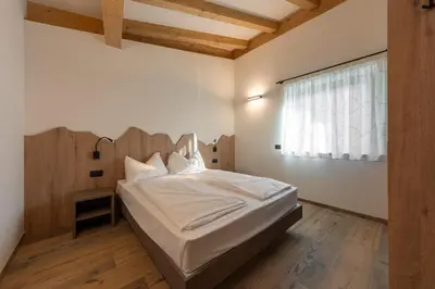 a bedroom with a bed with a wooden headboard and a window at Vacanze la Malga in Predazzo