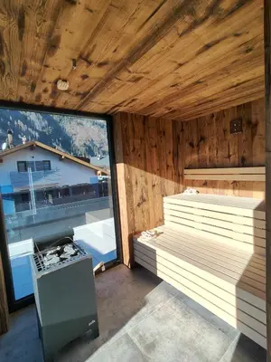 a sauna with a stove and a large window at Vacanze la Malga in Predazzo
