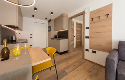 a kitchen and living room with a table and yellow chairs at Vacanze la Malga in Predazzo