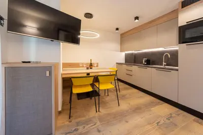 a kitchen with yellow chairs and a kitchen counter at Vacanze la Malga in Predazzo