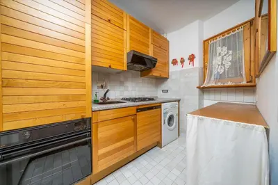 a kitchen with wooden cabinets and a washer and dryer at Le Gemelle Apartment in Cortina dʼAmpezzo