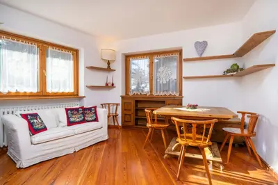 a living room with a white couch and a table at Le Gemelle Apartment in Cortina dʼAmpezzo