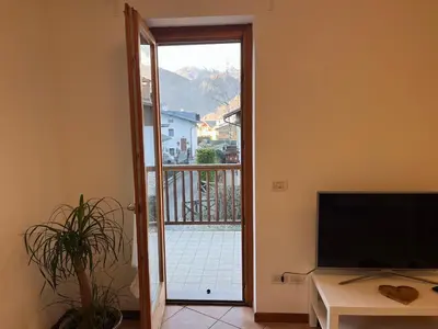 a living room with a door open to a balcony at Al Monte Zelo in Agordo
