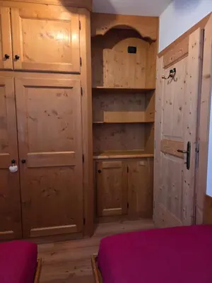 a room with wooden cabinets and a door and a bed at Meleres 11 in Cortina dʼAmpezzo