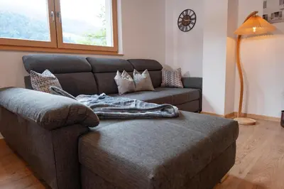 a living room with a couch and a table at Modern apartment with mountain views in Chiusa