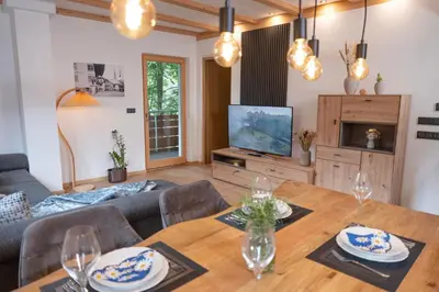 a living room with a table and a television at Modern apartment with mountain views in Chiusa
