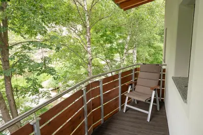 a balcony with a chair and trees at Modern apartment with mountain views in Chiusa