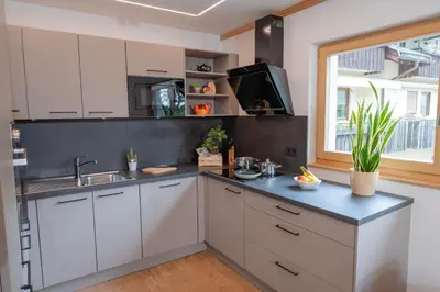 a kitchen with white cabinets and a sink and a window at Modern apartment with mountain views in Chiusa