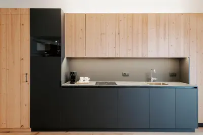 a kitchen with black cabinets and a sink at Garni Residence Alnö - Adults Only in San Vigilio Di Marebbe