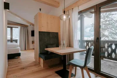 a room with a table and a chair and a bed at Garni Residence Alnö - Adults Only in San Vigilio Di Marebbe