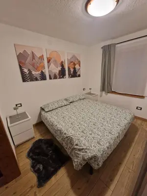 a bedroom with a bed with a comforter on the floor at Appartamento Federico in Rocca Pietore