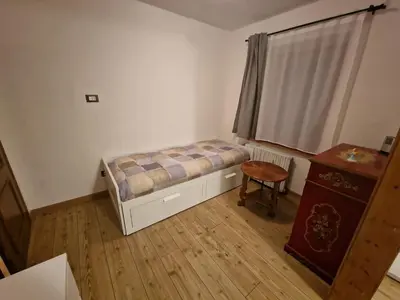 a small bedroom with a bed and a table at Appartamento Federico in Rocca Pietore