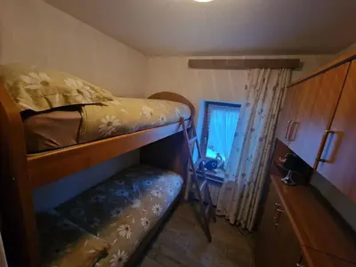 a small room with a bunk bed and a desk at Appartamento Federico in Rocca Pietore