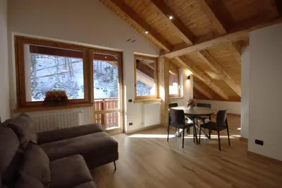 a living room with a couch and a table with chairs at Penthouse with view 2 bedrooms free parking in Cortina dʼAmpezzo