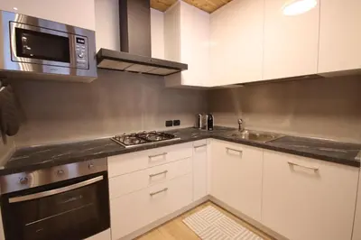 a kitchen with white cabinets and a microwave at Penthouse with view 2 bedrooms free parking in Cortina dʼAmpezzo