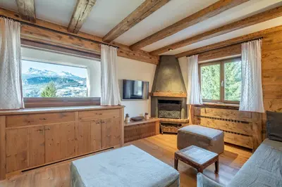 a living room with a large window and a fireplace at Apartment Capriol by My Villa Collection in Cortina dʼAmpezzo