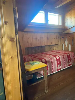 a small room with a bed and a chair at 360-degree panoramic attic in Cortina in Cortina dʼAmpezzo