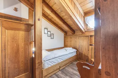 a small bedroom with a bed in a room with wooden walls at Casa Funivia 2, with panoramic balcony in Cortina dʼAmpezzo