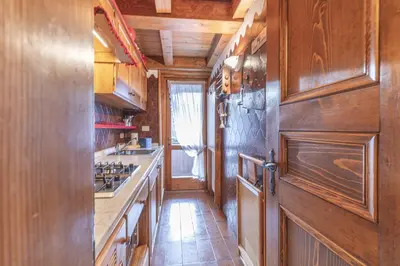 a kitchen with wooden cabinets and a stove top oven at Casa Funivia 2, with panoramic balcony in Cortina dʼAmpezzo
